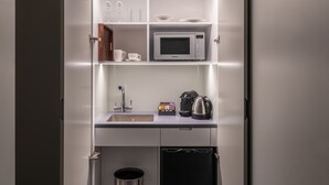 Een kleine keuken met een magnetron, koffiezetapparaat en spoelbak.