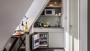 Una cocina compacta con microondas integrado, un refrigerador pequeño y una zona de comedor con mesa y sillas.