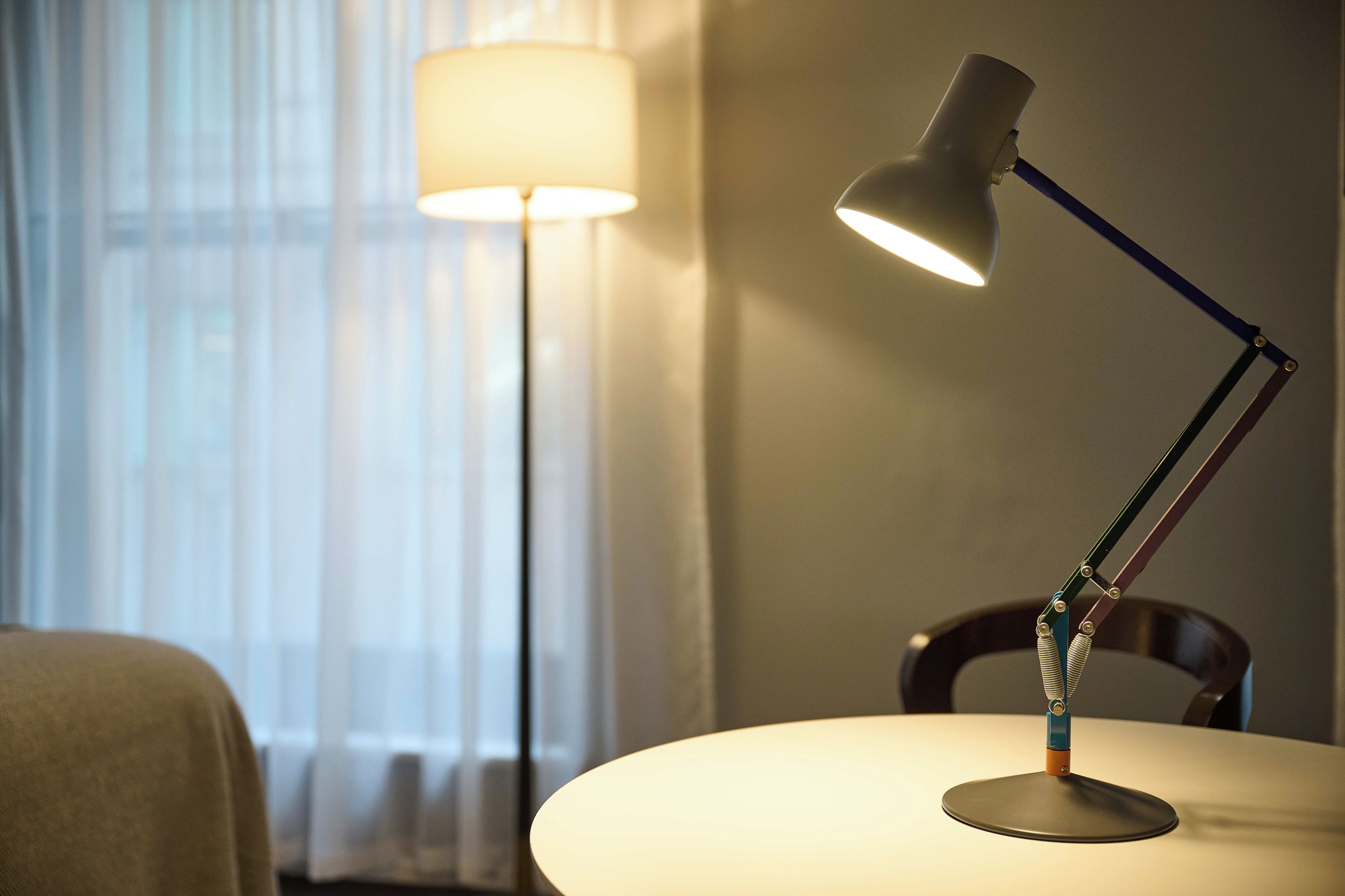 A room with a table, a lamp, and a chair.