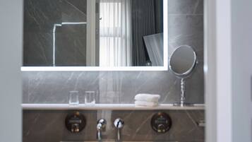 A modern bathroom with a marble sink, a mirror, and a towel rack.