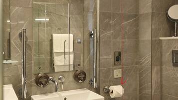 A modern bathroom with a large mirror, a sink, a toilet, and a shower area.