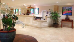A reception area with a counter, potted plants, and artwork on the walls. - Rare Unobstructed Diamond Head-Ocean Views, Best location, Pool, 1 minute to Beach (Honolulu)