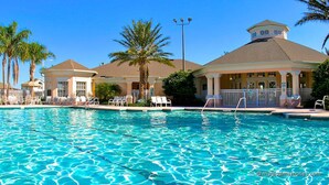 A swimming pool with clear blue water, surrounded by lounge chairs and palm trees. - Royal Palm Villa (Kissimmee)