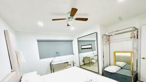 Hotellihuone, jossa on sänky, työpöytä, tuoli, peili, kattotuuletin ja vaatekaappi.