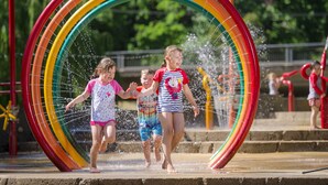 Niños jugando en un parque acuático con un tobogán de agua arcoíris gigante.