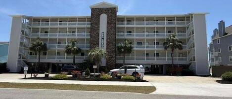 A multi-story hotel with a central tower, balconies, and palm trees.