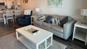 Ein Wohnzimmer mit Sofa, Couchtisch und einem Essbereich mit Stühlen und Tisch.