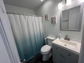 Une salle de bain avec des toilettes, un lavabo et un rideau de douche.