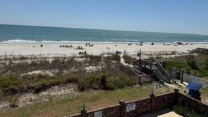 Ein Strand mit einer Holzpromenade, die zu einem Pavillon führt.