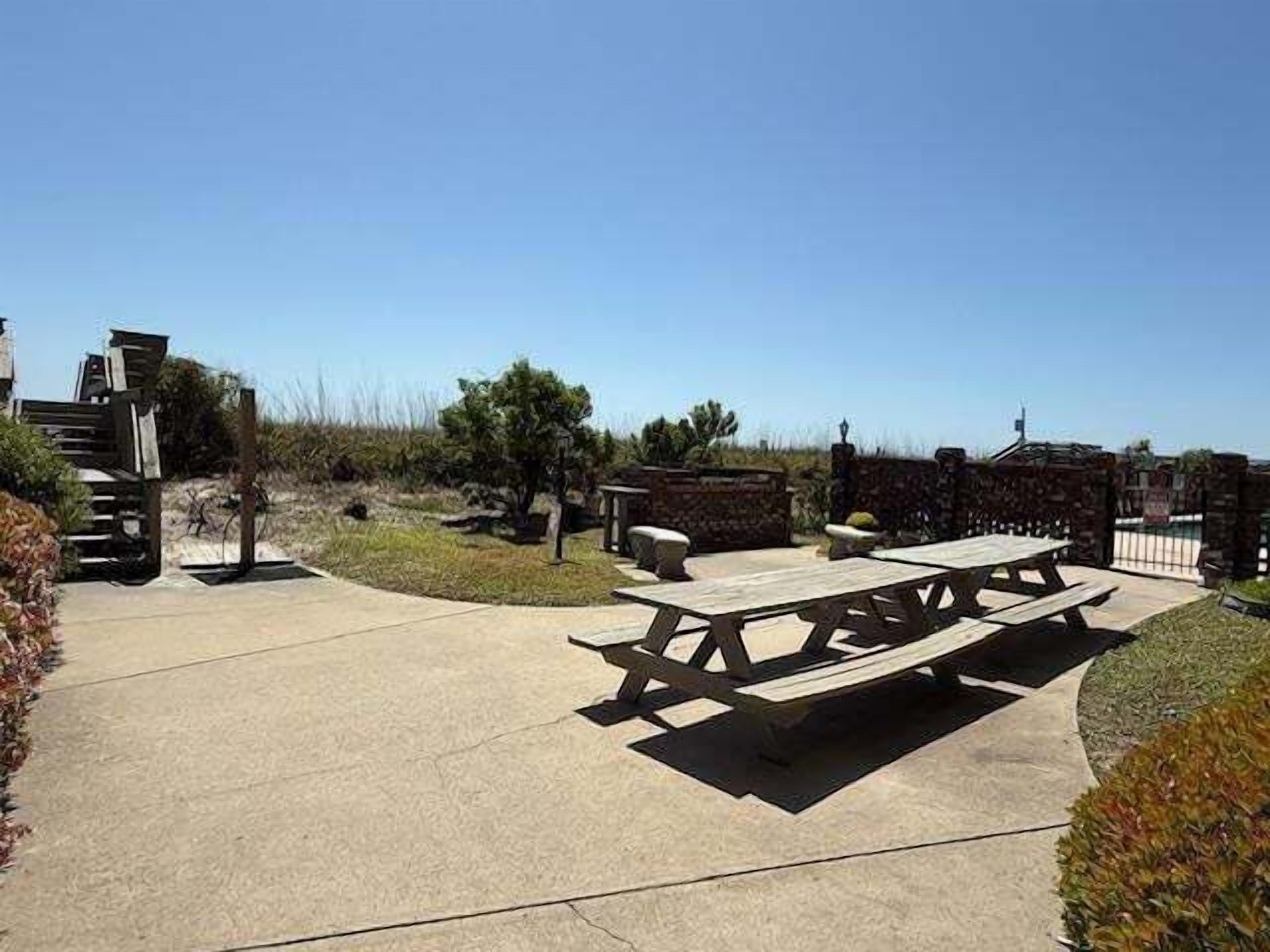 An outdoor patio area with picnic tables and a stone wall.