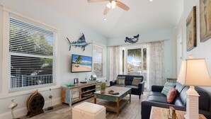 Un salon spacieux doté d’une grande fenêtre, d’un ventilateur de plafond et offrant une vue sur l’extérieur.