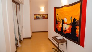 Un pasillo con piso de baldosas, un cuadro en la pared y una pequeña mesa con un libro.