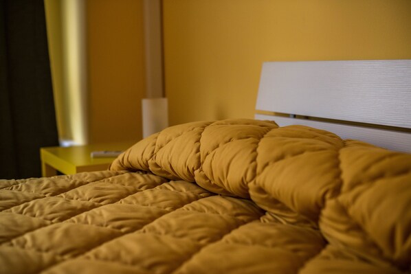 A bed with a yellow quilt and a white headboard. - Loft Notarbartolo 2 (Palermo)