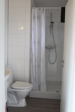 A bathroom with a toilet, shower, and bathtub. - Systrakot (Talknafjordur)