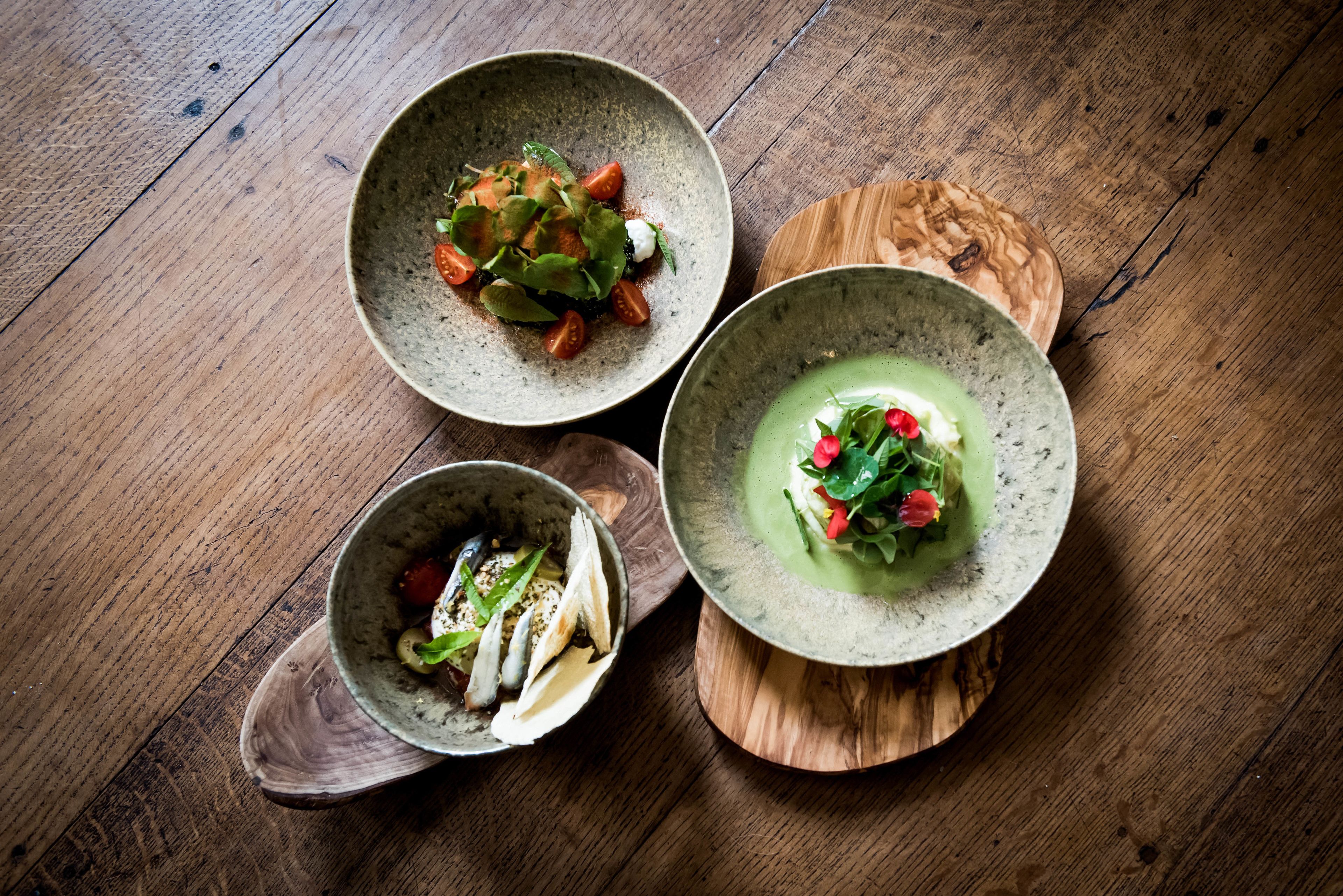 Three bowls of food on a wooden table.