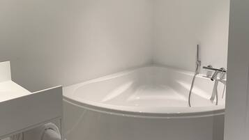 A modern bathroom with a freestanding bathtub, a white sink, and a towel rack.