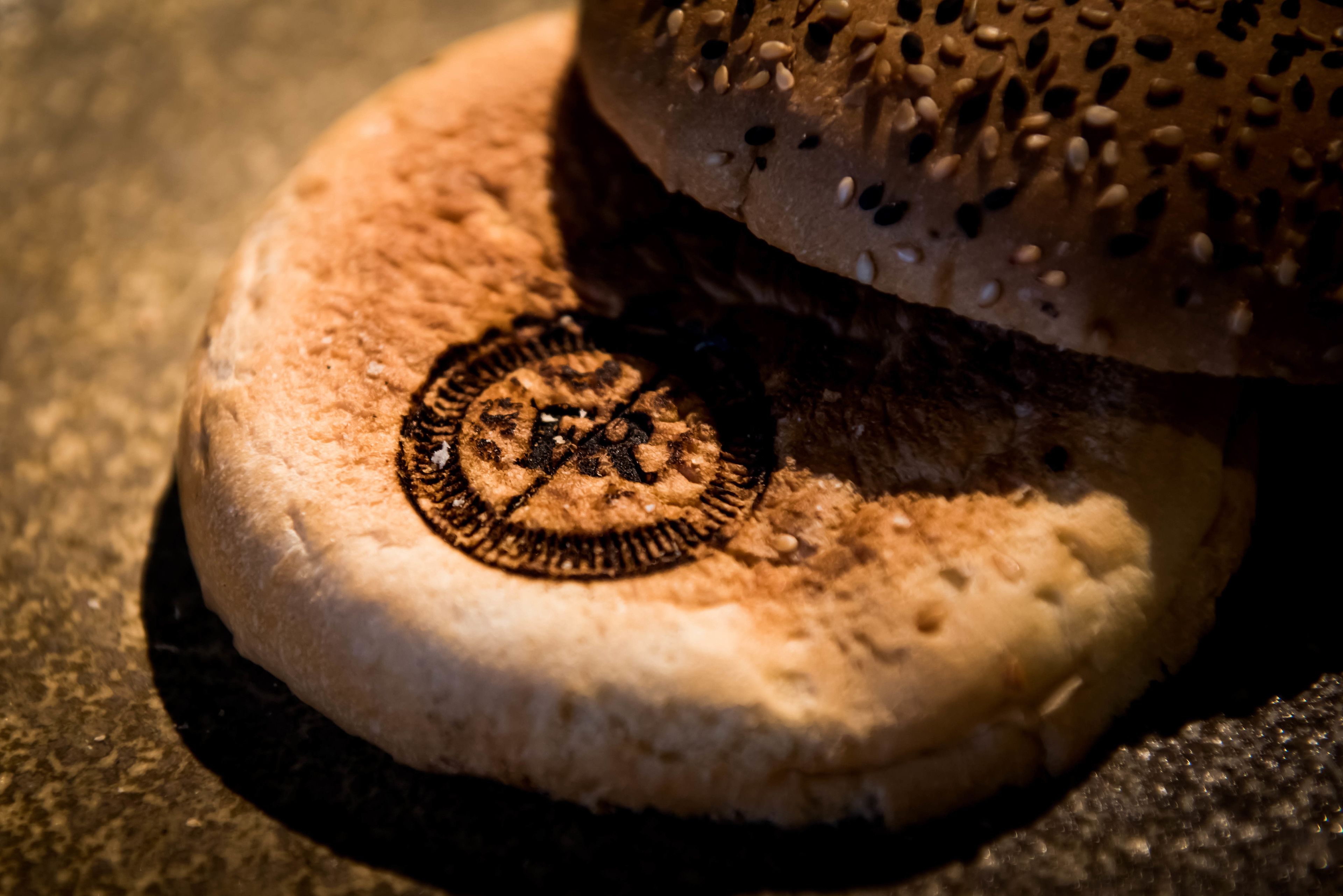 A close-up of a bread with sesame seeds and a circular design on its crust.