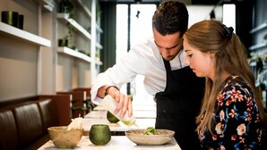 L’intérieur d’un restaurant avec un comptoir en marbre, un bol vert et une bouteille que tient une personne.