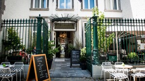Un restaurant avec une terrasse, un menu écrit à la craie et une porte verte.