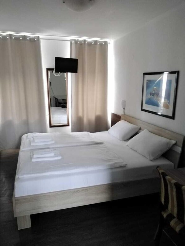 A neatly made bed with white linens, a wooden headboard, and a framed picture on the wall.