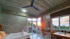 Ein Schlafzimmer mit Bett, Schreibtisch und Stuhl. Ein Fenster bietet Blick ins Freie.