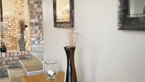 A hallway with a wooden bench, a vase with branches, and two glass candle holders. - Coastal Haven 4 (Gqeberha (Port Elizabeth))
