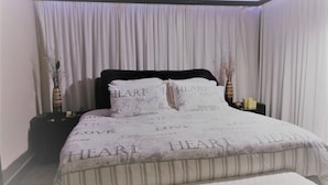 A bedroom with a bed, a bedside table, and a nightstand. - Coastal Haven 4 (Gqeberha (Port Elizabeth))