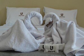 A hotel room with two white towels shaped like swans and a set of toiletries on the bed. - Pousada Ubarana (Maragogi)
