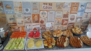 A buffet counter with various food items and a wall decorated with vintage food-related signs. - Pousada Ubarana (Maragogi)