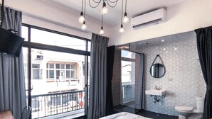 A modern bedroom with a large bed, a bathroom with a mirror and sink, and a balcony with a view of buildings. - The Gatsby Apartment (Tainan)
