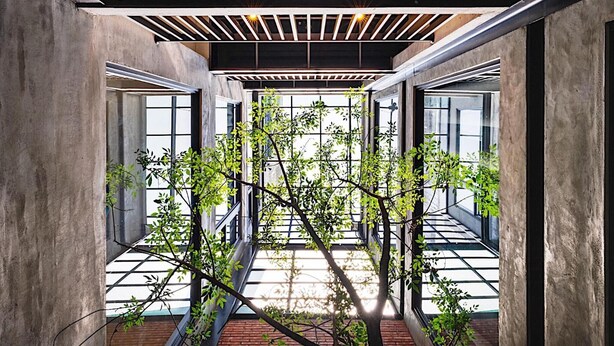 A modern interior with concrete walls, a wooden ceiling, and a view through a glass door to a brick floor. - The Gatsby Apartment (Tainan)