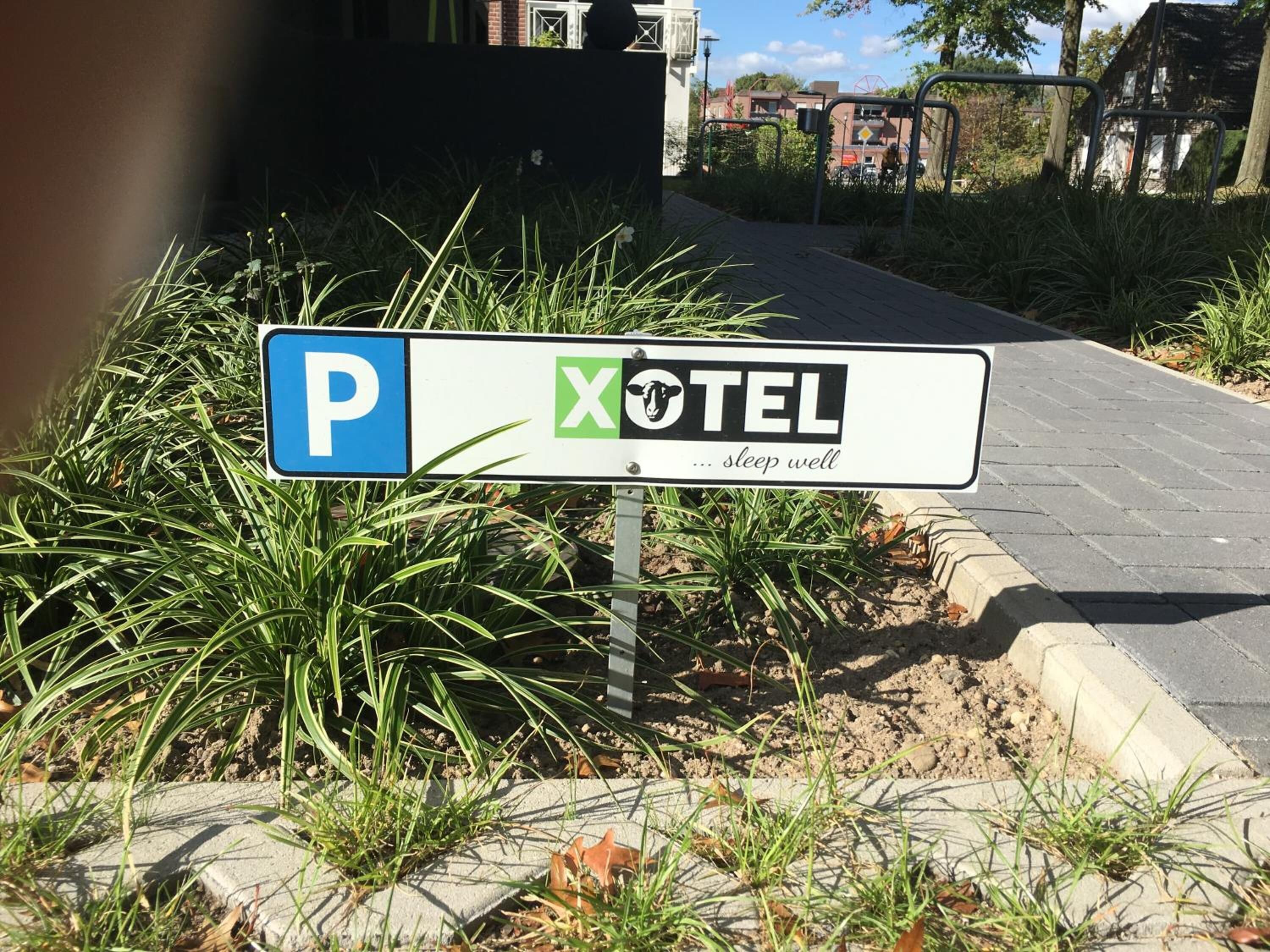 A sign for a hotel with a 'P' indicating parking, a logo with a sheep, and the text 'XOTEL ... sleep well'.