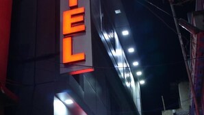 Ένα ξενοδοχείο με μια μεγάλη, ευδιάκριτη επιγραφή που γράφει «ΞΕΝΟΔΟΧΕΙΟ» με έντονα πορτοκαλί γράμματα.