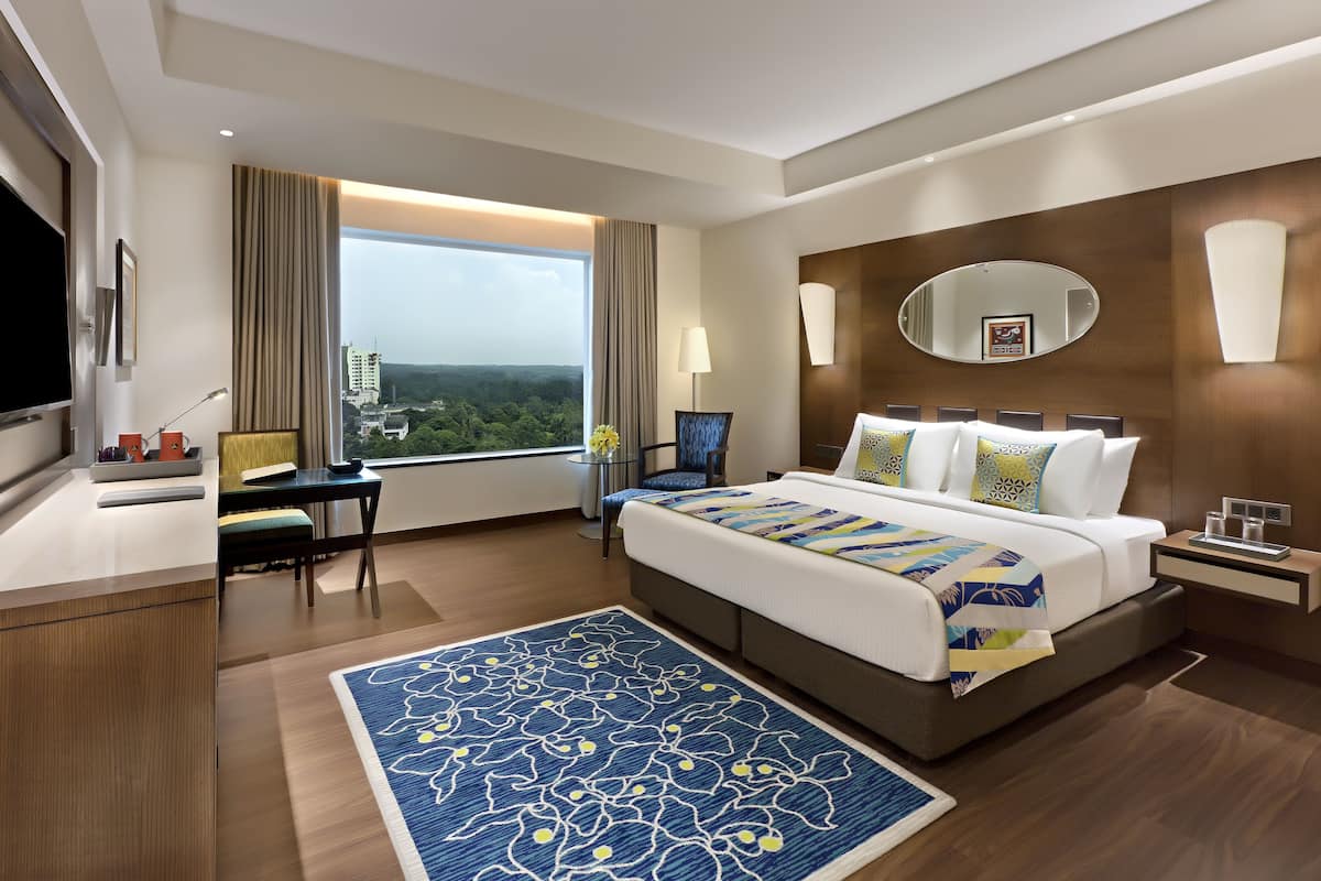 Une chambre d’hôtel moderne, dotée d’un grand lit, d’un bureau et offrant une vue sur la ville.