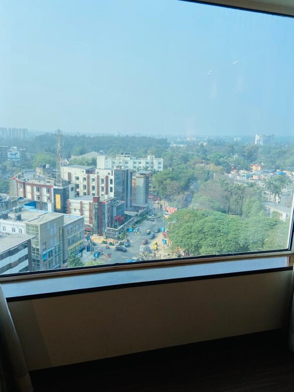 A view from a window of a cityscape with buildings, roads, and greenery.