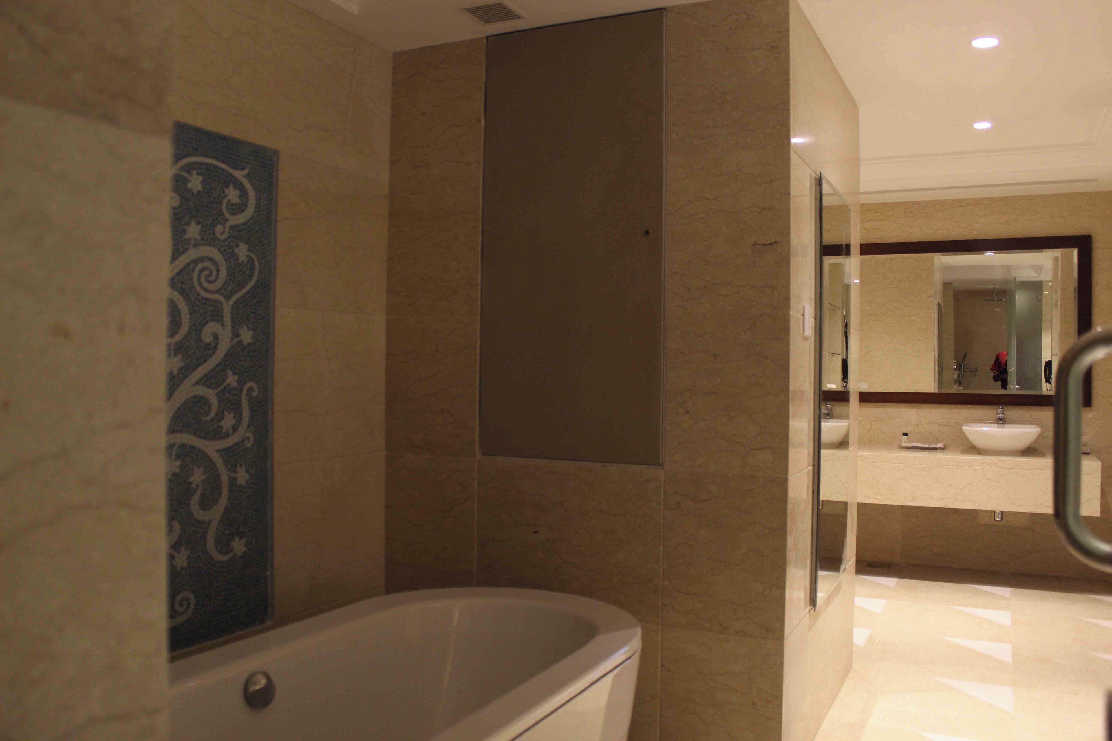 Un baño moderno con una bañera independiente, un espejo grande y un tocador con lavabo.