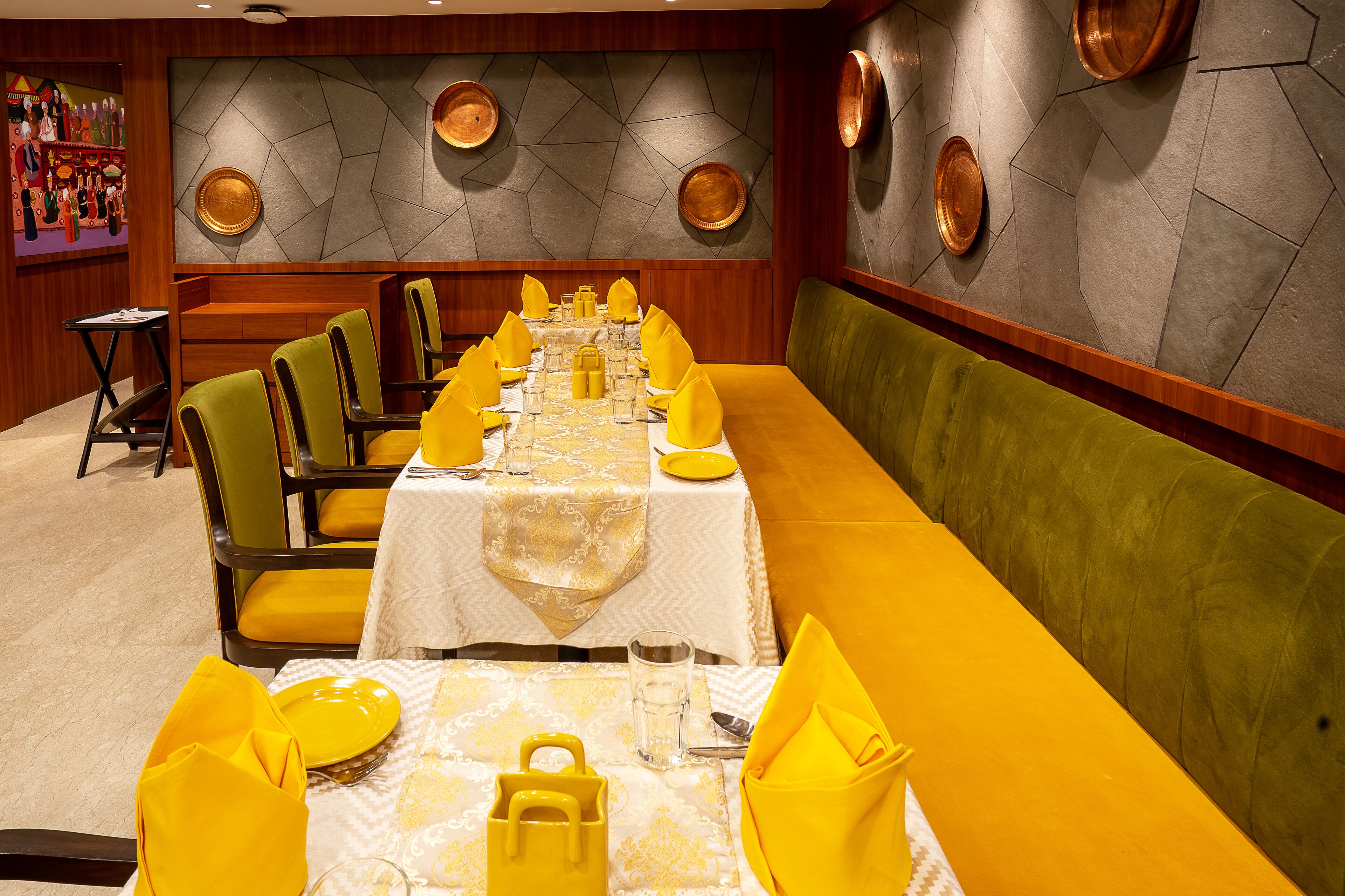 Comedor con una larga mesa dispuesta para varios invitados, con servilletas amarillas y un mantel estampado.