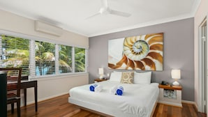 A hotel room with a bed, a desk, and a window with blinds. - Beachfront Apt In Alamanda Beachfront Resort 25 (Palm Cove)