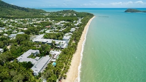 An aerial view of a coastal resort with beachfront properties, a pier extending into the sea, and lush greenery. - Beachfront Apt In Alamanda Beachfront Resort 25 (Palm Cove)
