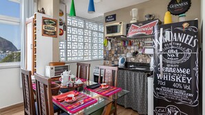 A dining area with a table set for two, a bar area with various bottles, and a chalkboard sign advertising Jack Daniel's whiskey. - Moderno Apartamento na Praia de Botafogo (Rio de Janeiro)