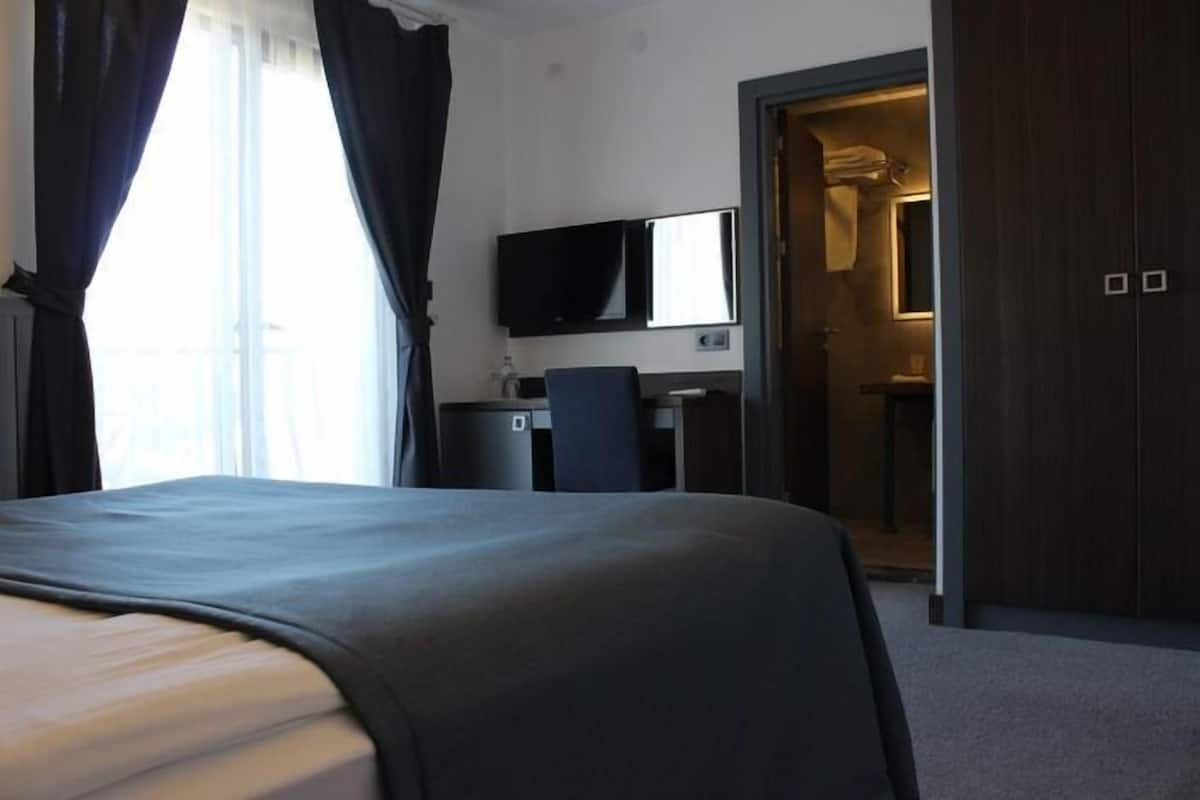 A hotel room with a bed, a desk, a television, and a wardrobe.