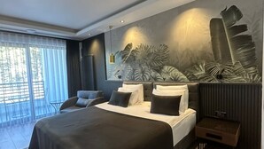 A modern bedroom with a large bed, a seating area, and a view of the outdoors. - Amorium Hotel (Kastamonu)