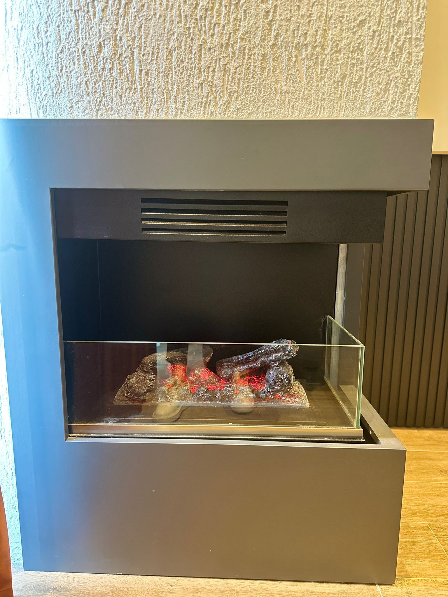 Ein Kamin mit einer Glaseinfassung, die einen dekorativen Gegenstand enthält.