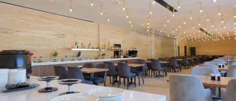 Een modern restaurant met een lange toonbank, meerdere tafels en stoelen.