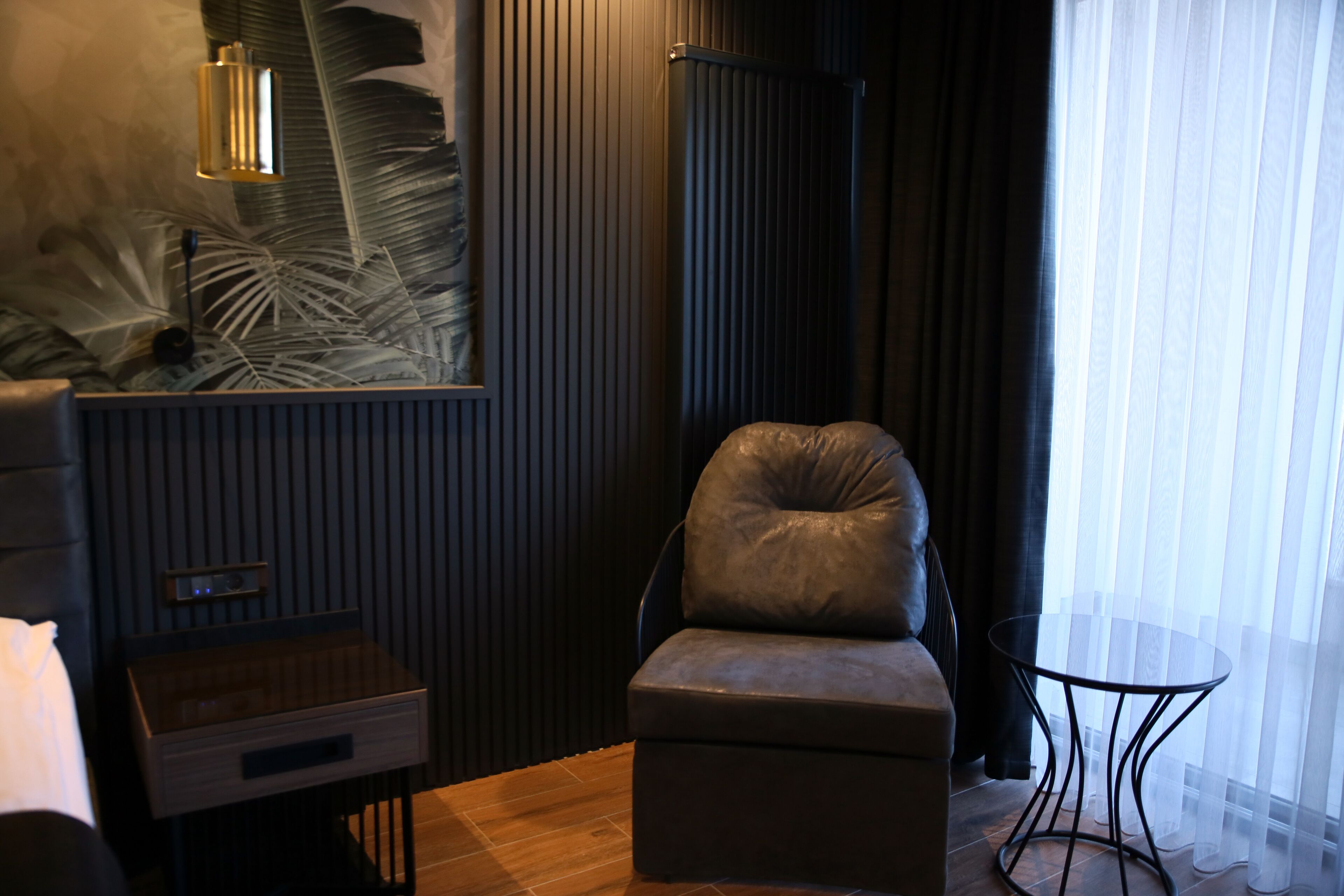 Una habitación moderna con un sillón de cuero, una mesita de madera, una mesa de vidrio y un cuadro abstracto grande en la pared.