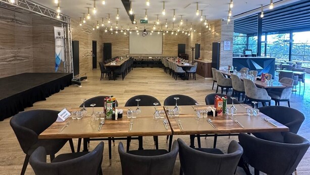 A conference room with a long table, chairs, a stage, and a projector screen. - Amorium Hotel (Kastamonu)