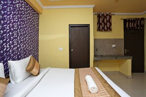 A hotel room with a bed, a bathroom with a sink and mirror, and a door.