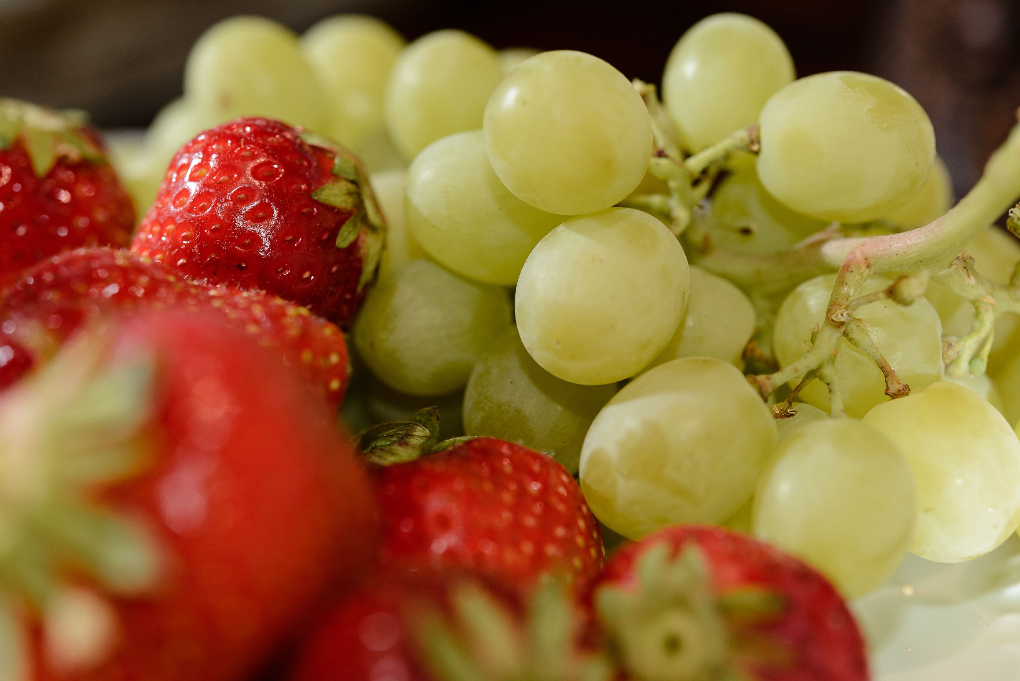 A close-up of a fruit bowl containing strawberries and green grapes.