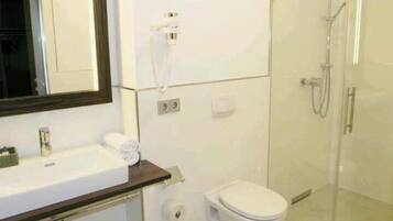 Un baño con lavamanos blanco, espejo, inodoro y ducha.