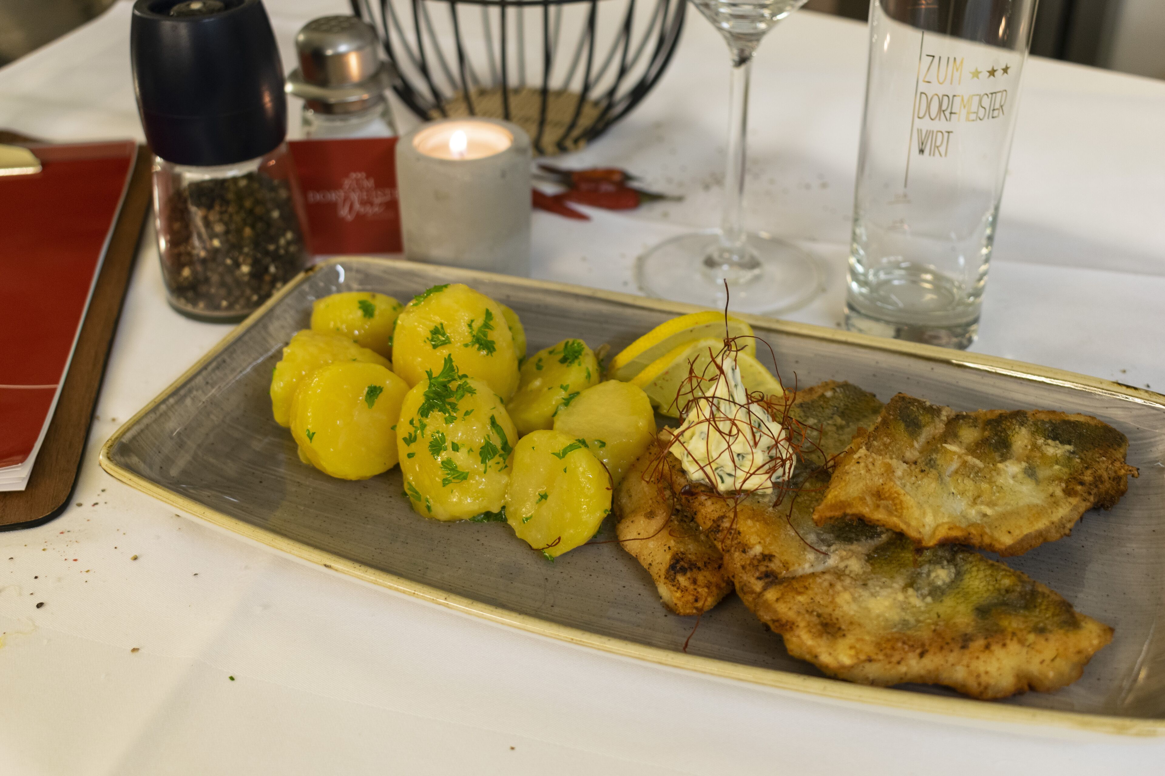 A plate of food with potatoes and fish on a table.